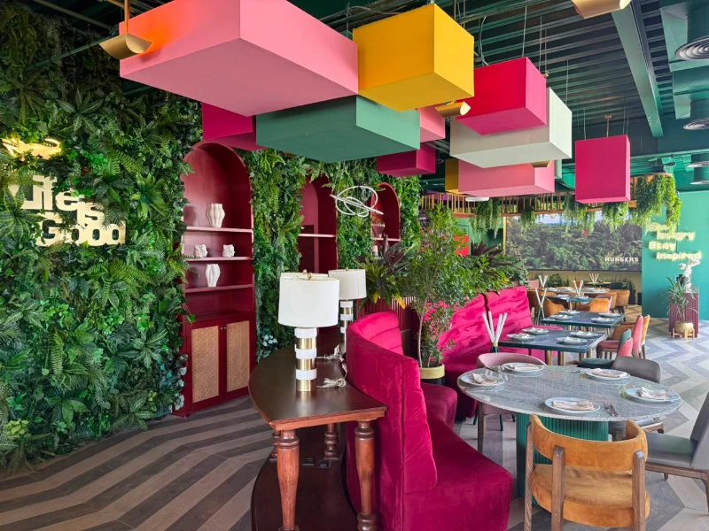 El rincón de las cajas de Hungers. Volúmenes de color colgados sobre el verde, y las butacas fucsia.