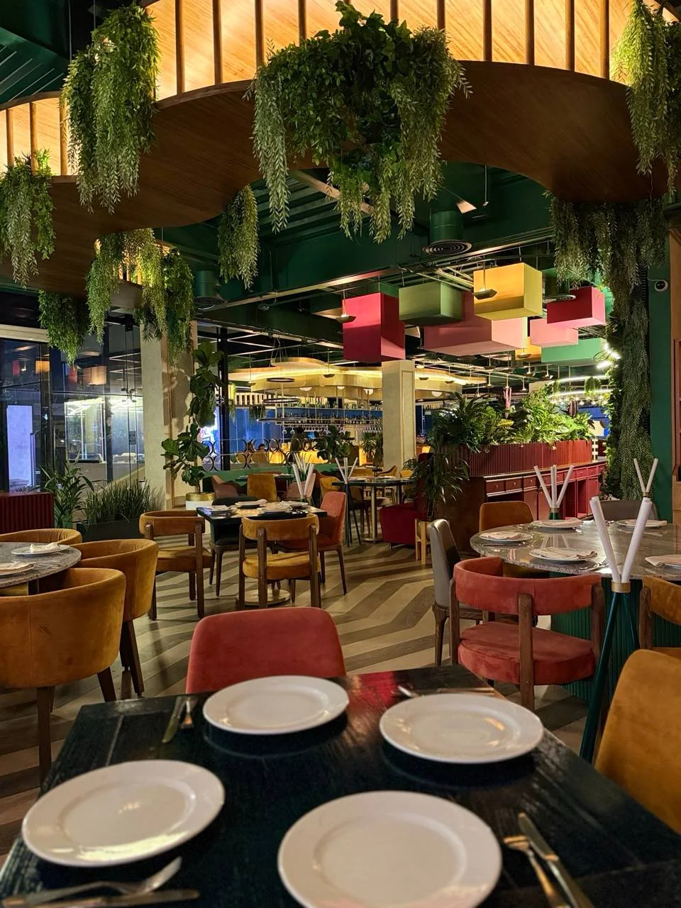 El salón bajo el arco de madera, con plantas colgando del techo.
