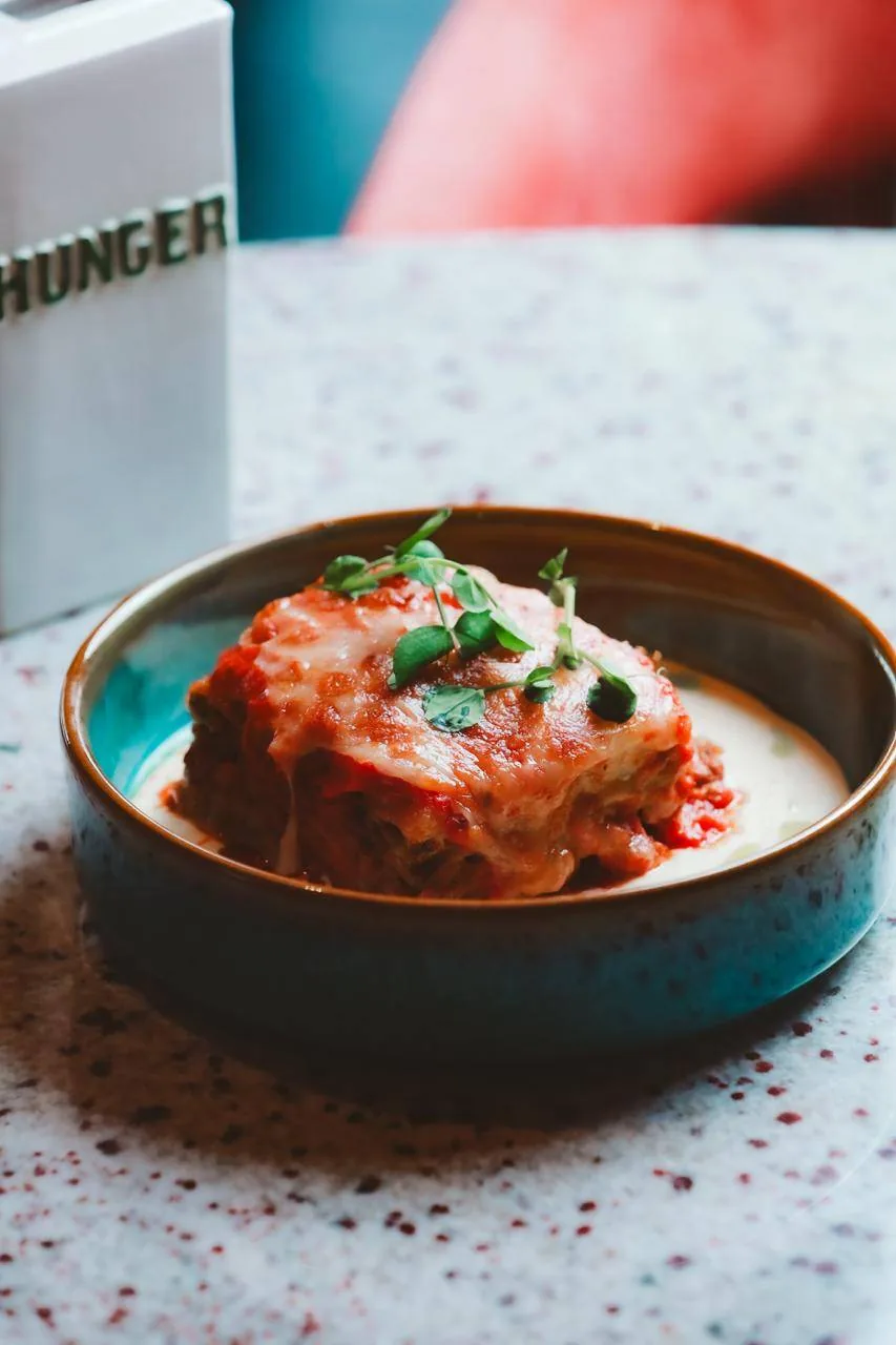 Lasaña gratinada en cazuela de cerámica azul.