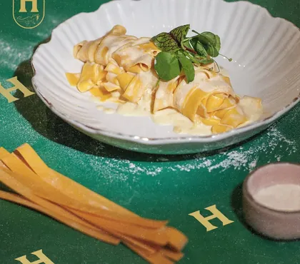 Pappardelle en salsa cremosa, con listones de pasta fresca al lado.