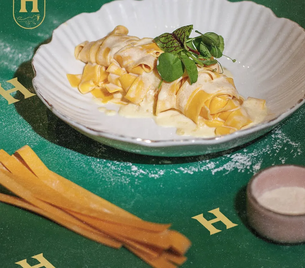 Pappardelle en salsa cremosa, con listones de pasta fresca al lado.
