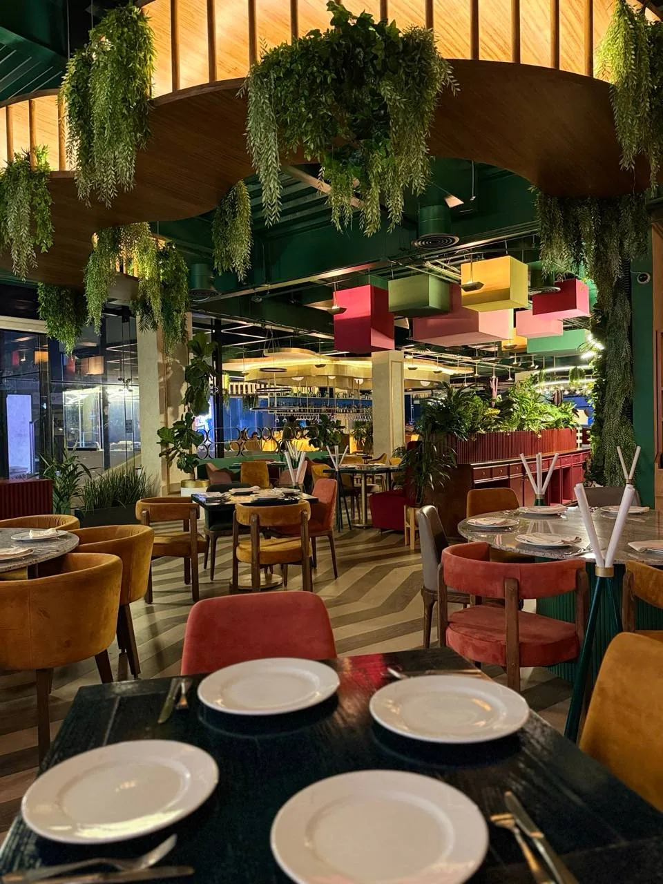 El salón de noche bajo el arco de madera con las plantas colgantes.