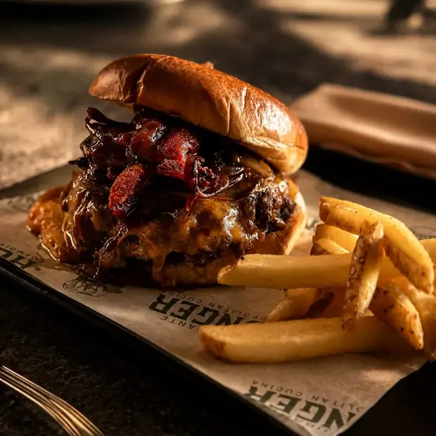 La hamburguesa de la casa con tocino y papas, sobre papel estraza.