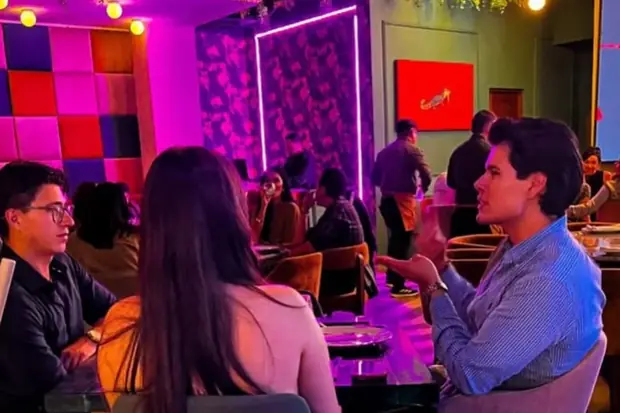El salón de noche, con los neones encendidos y las mesas llenas.